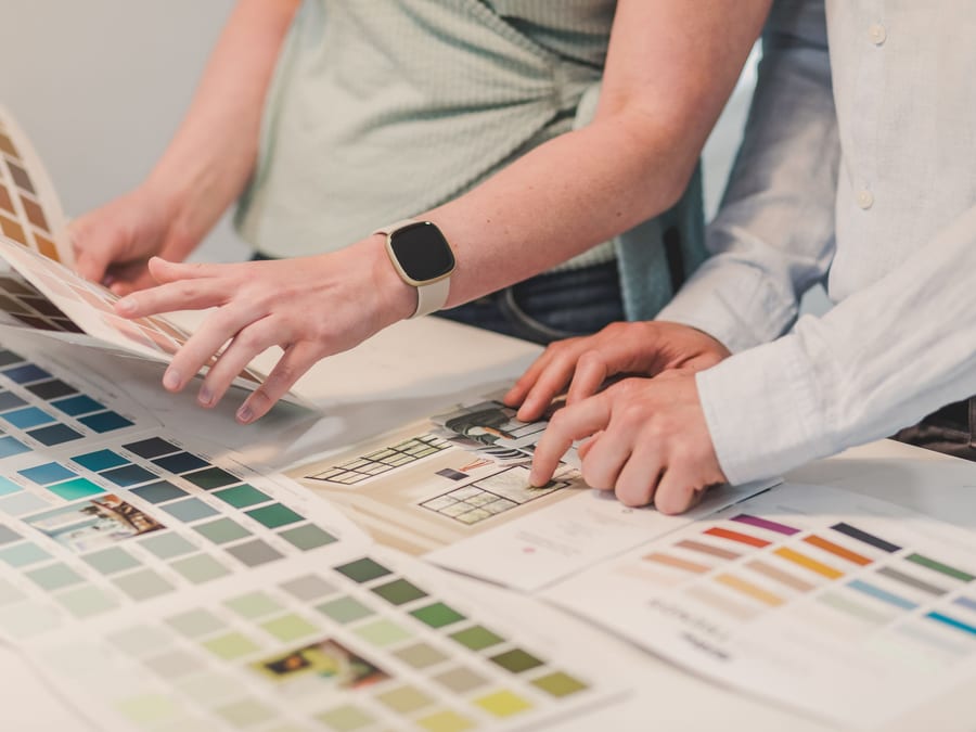 Colour samples and drawings spread across a table mid-conversation.