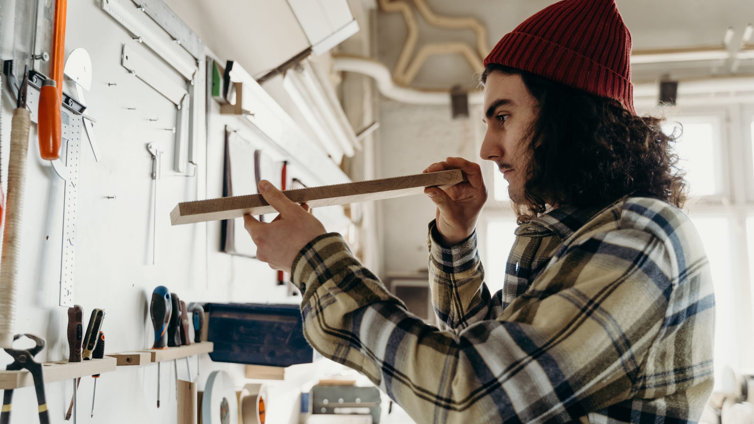 Someone in a workshop sighting along the length of a piece of trim, checking it for straightness before it is used.