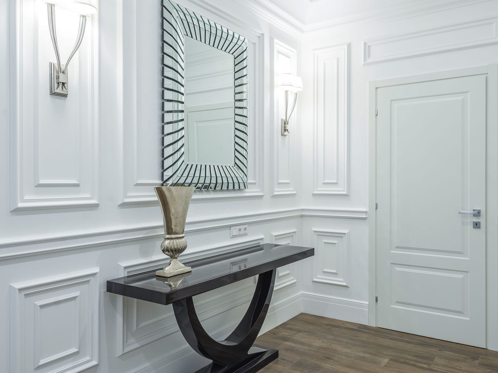 A painted entry hall set with applied moulding panels and wainscoting, every edge and corner meeting cleanly in soft light.