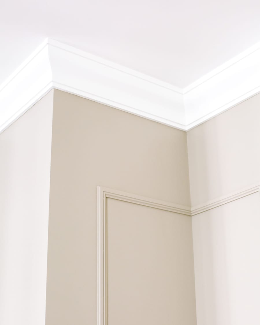 The precise edge where a painted wall meets a white ceiling, held straight and clean.
