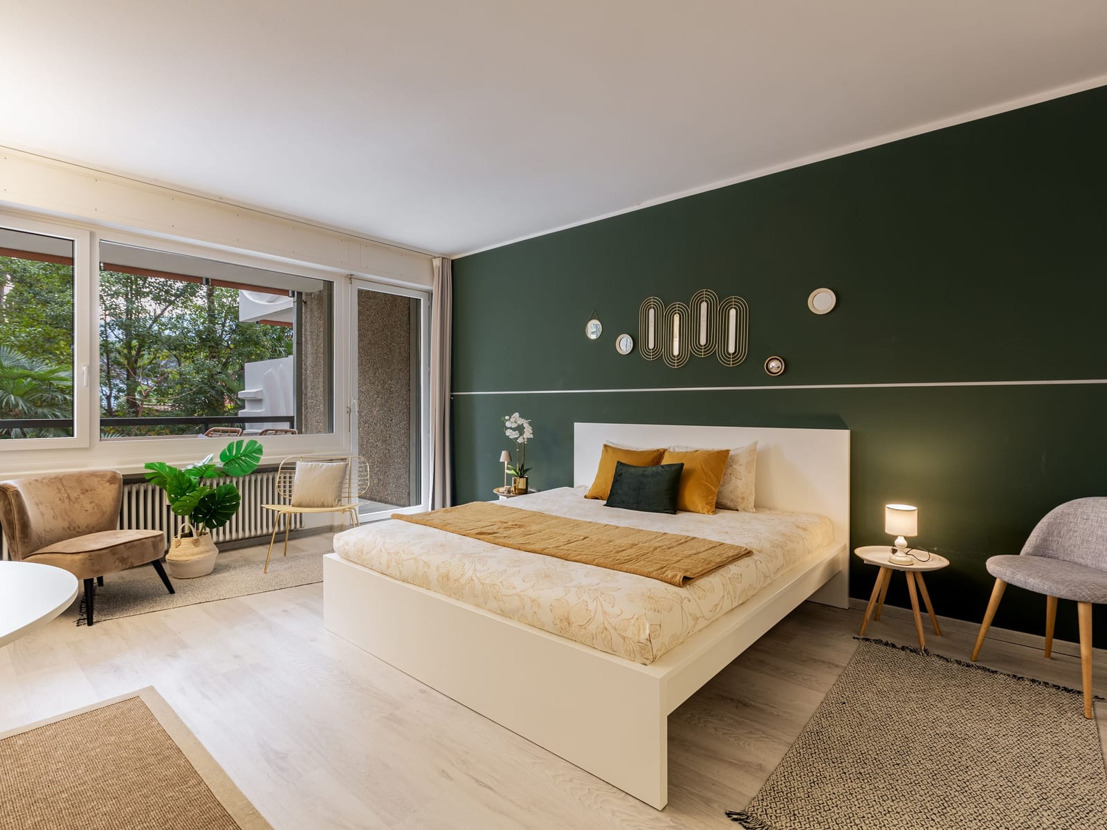 A deep green accent wall behind a low bed, the colour held flat and even to a clean edge at the ceiling.
