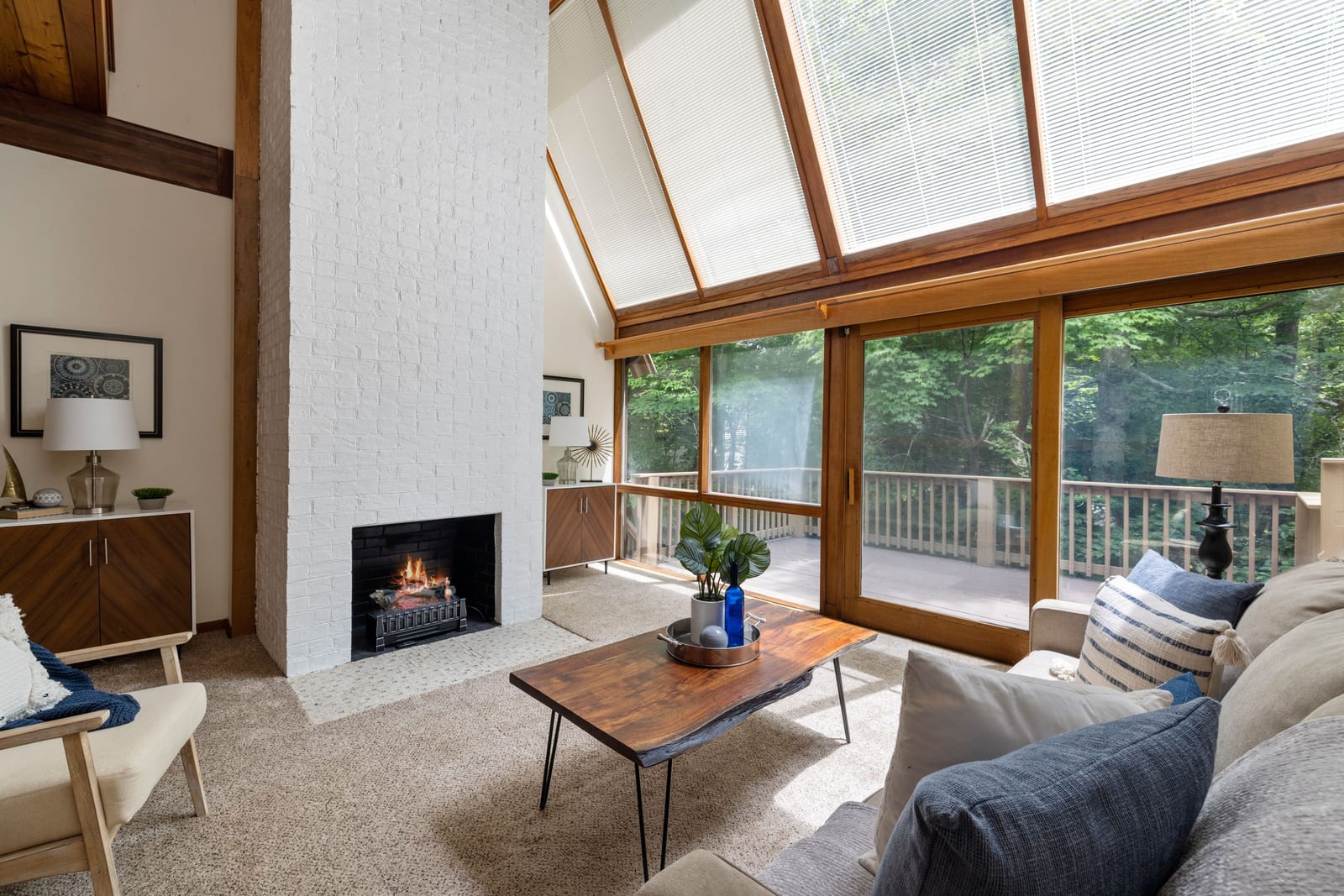 A finished Wasilla residence interior, a pale fireplace between tall windows onto the trees.