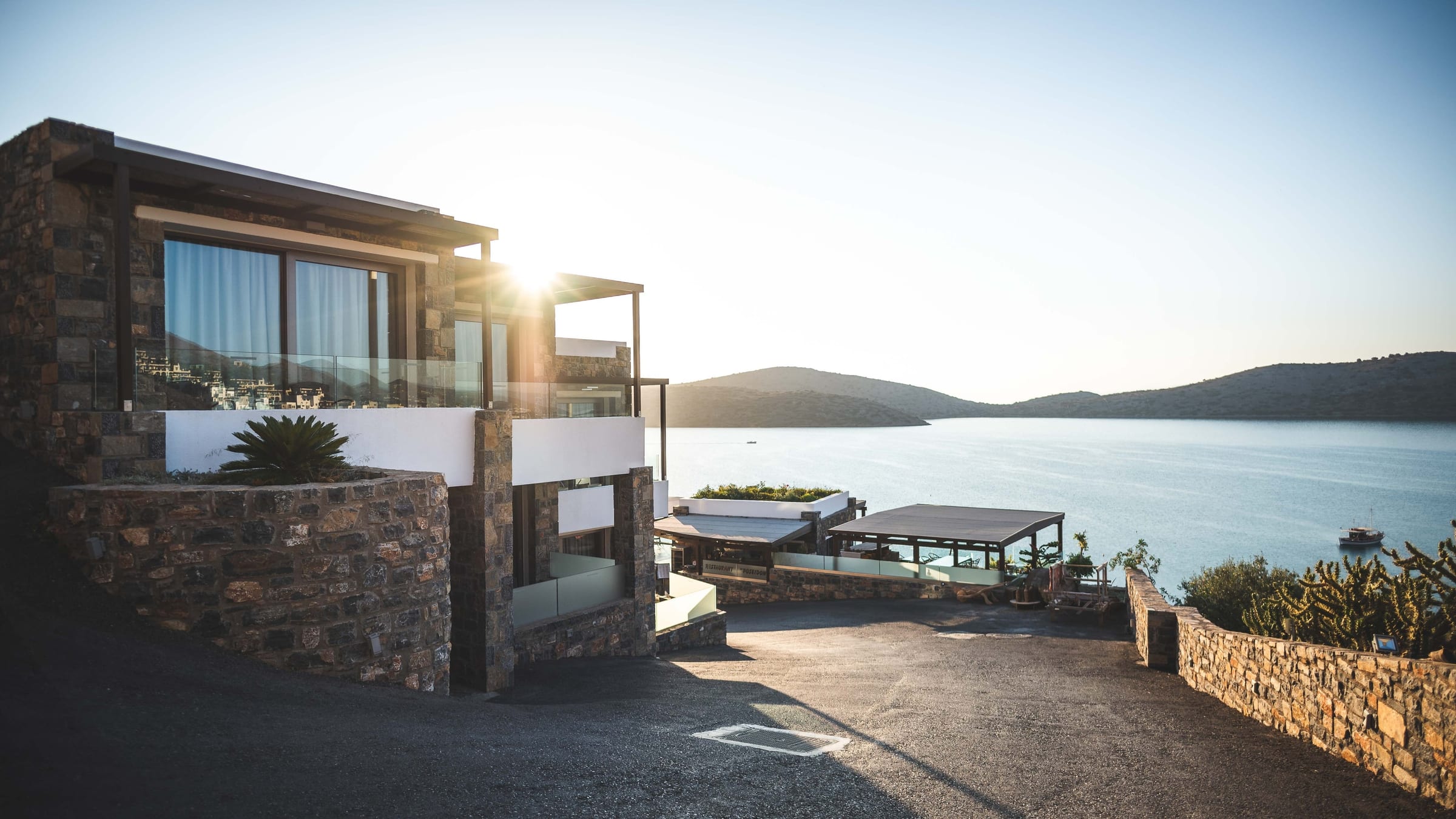 A stone and glass residence above a mountain lake at first light, its exterior trim and siding finished to a crisp, even line.