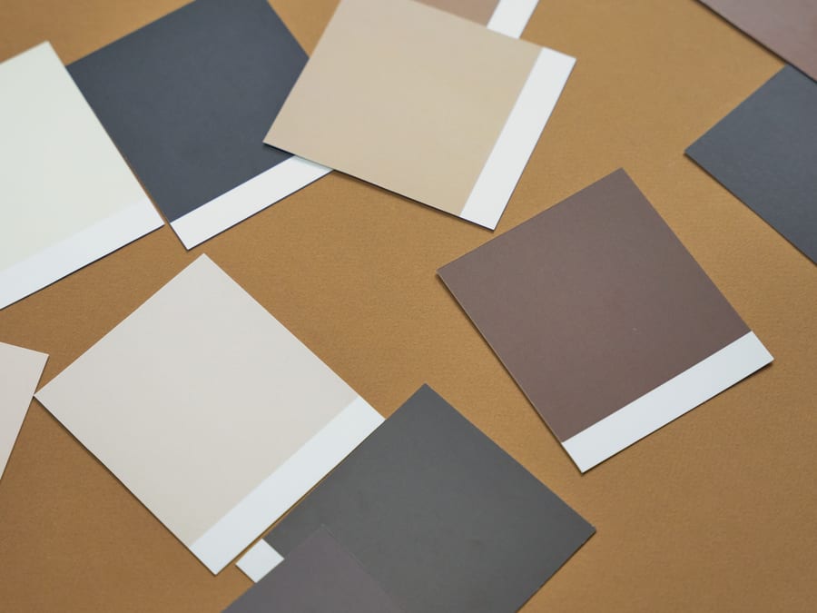 Colour samples and a project schedule laid out on a work surface in daylight.