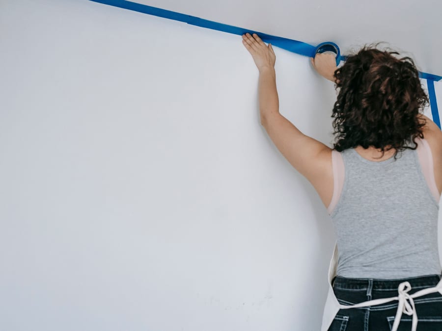 Painter's tape being pressed along a wall edge to establish a clean line.