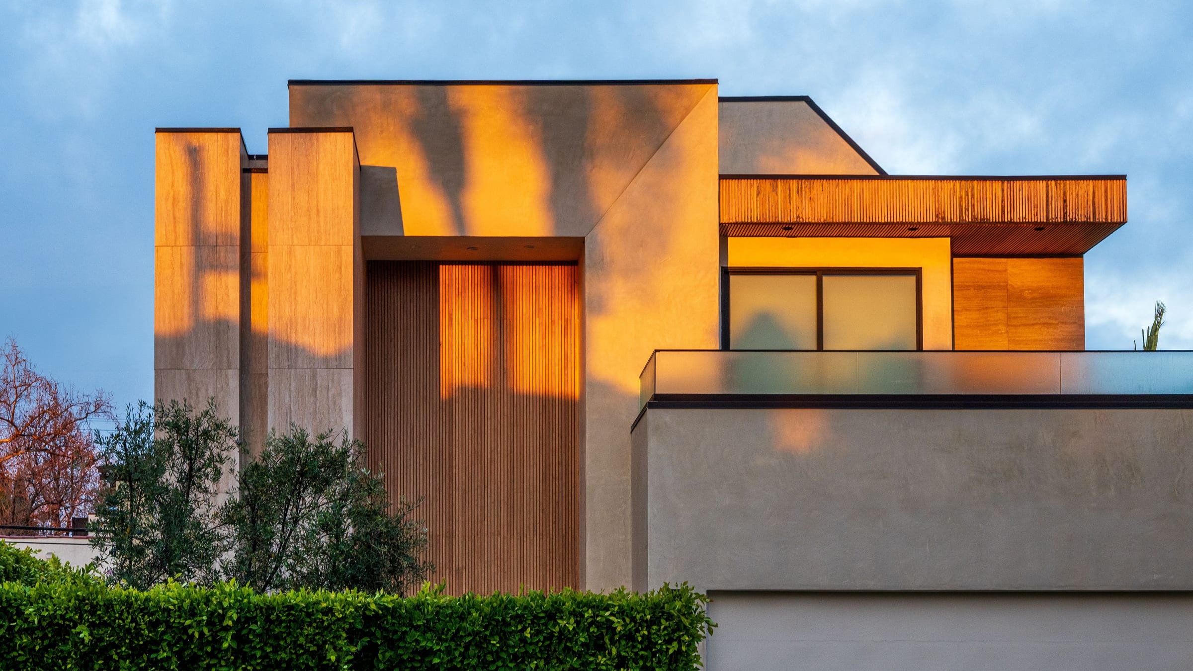 A mountain modern estate at golden hour, its full exterior elevation newly finished in deep, even tones.