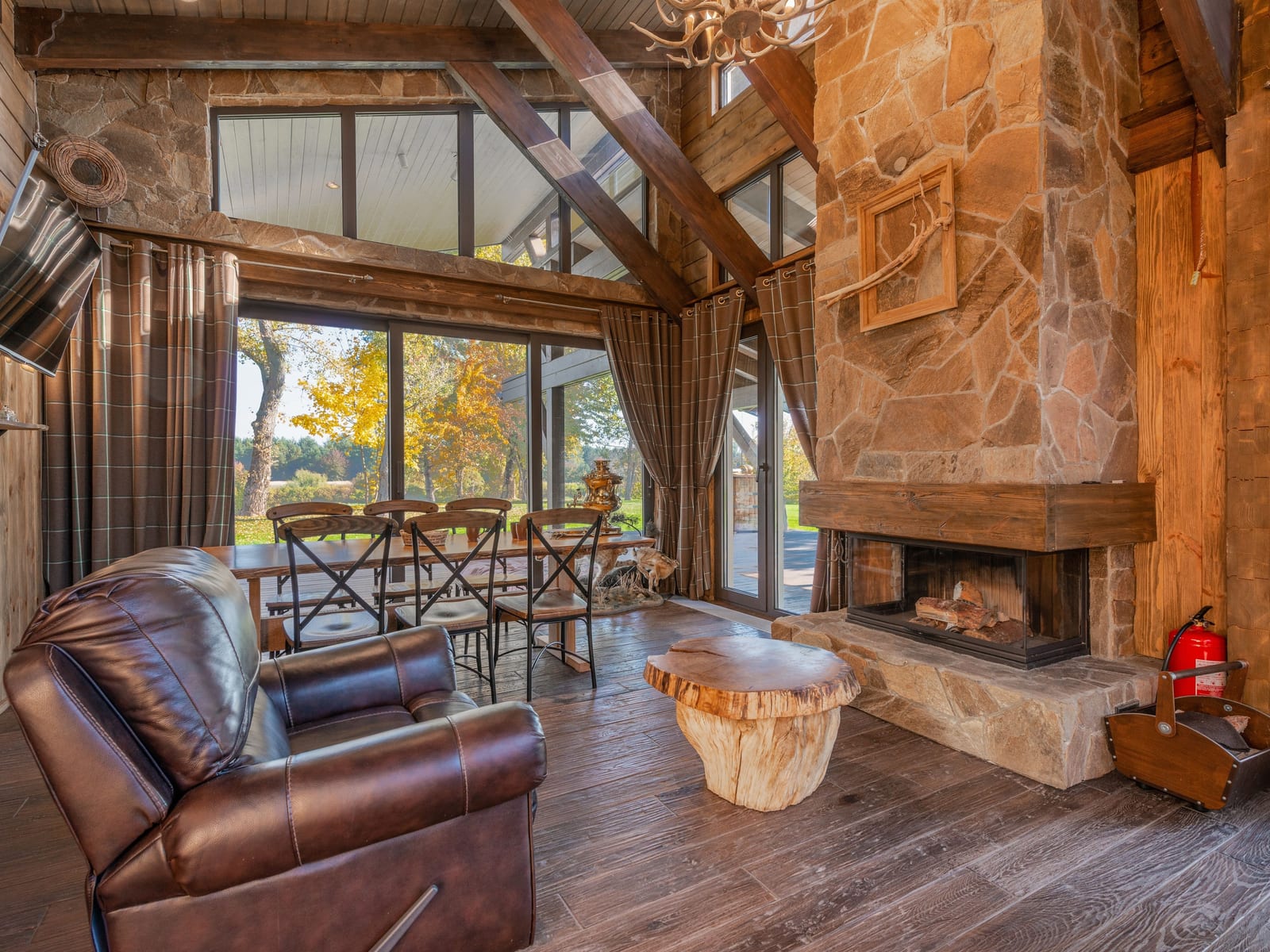 A timber lodge great room with a stone fireplace rising to a vaulted, finished ceiling.