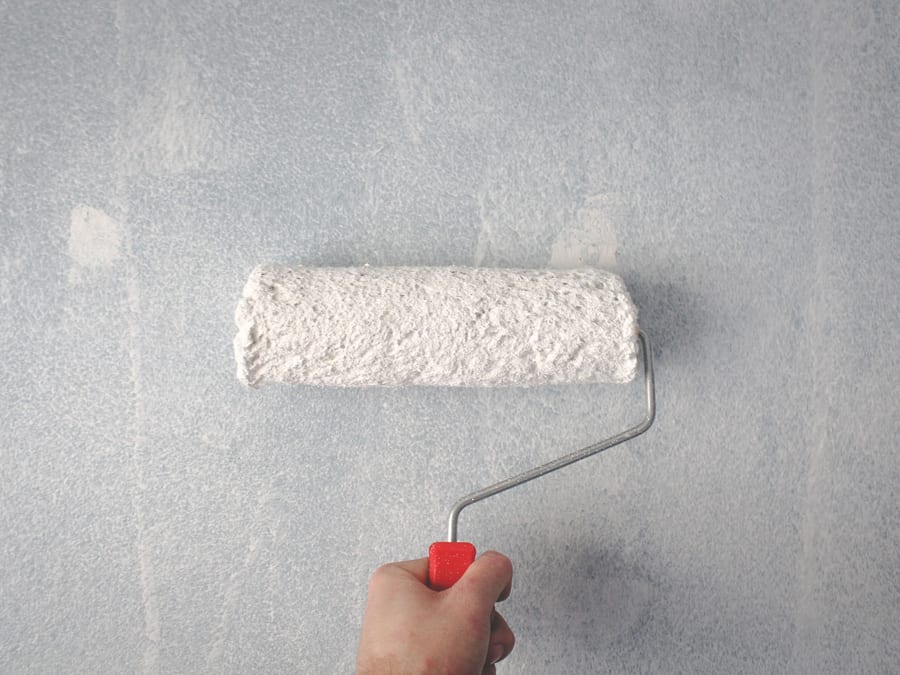 A roller drawing a fresh, even coat across a prepared wall.