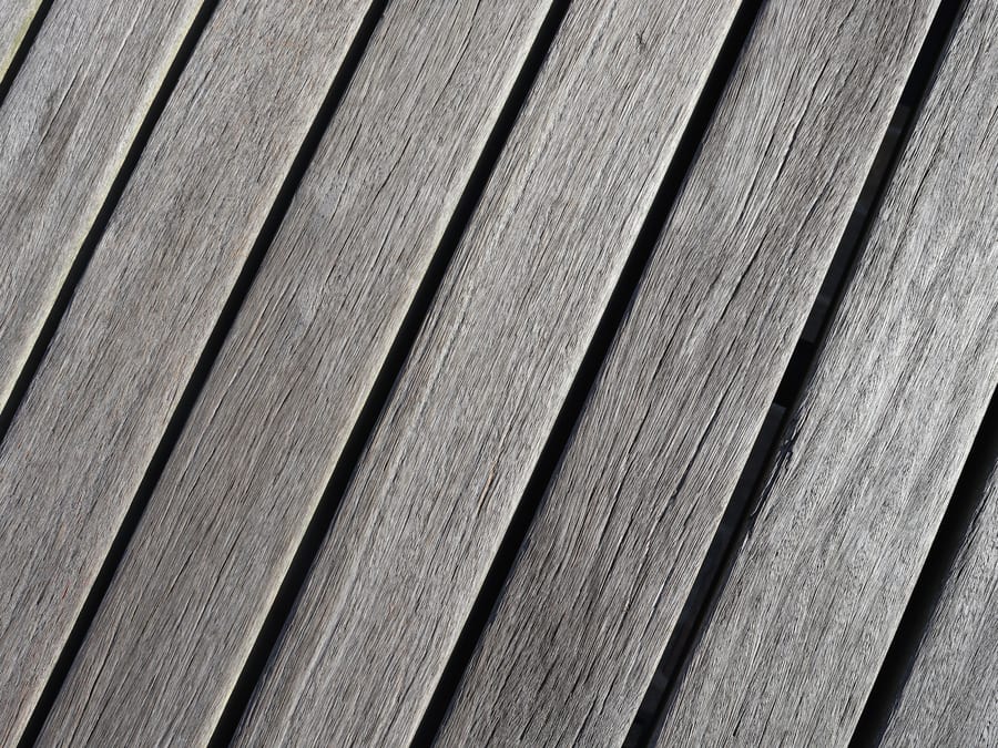 Weathered exterior decking, the timber greyed and ready to be cleaned back before it is refinished.